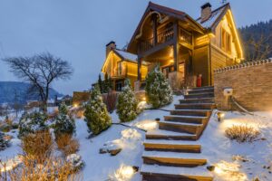Cozy wooden chalet in snowy mountains, warmly illuminated during twilight.